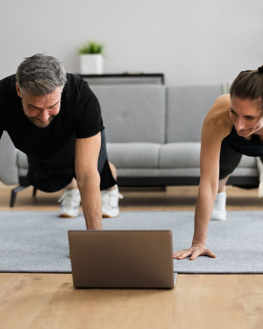 couple working out at home with a laptop in front of them